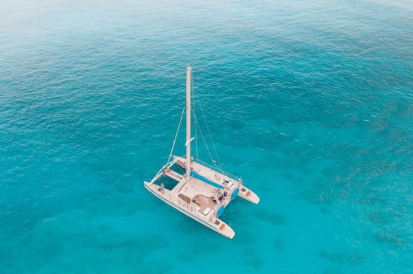 Aerial view of a catamaran sailing in crystal-clear turquoise water