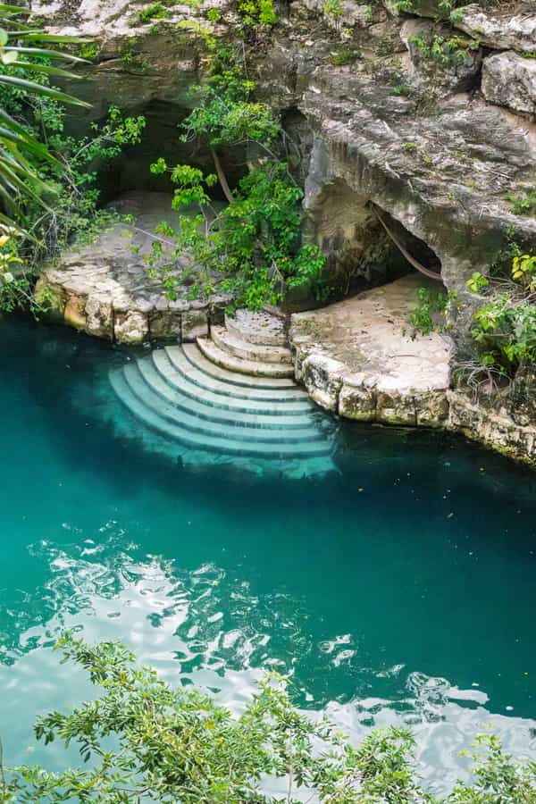 Turquoise cenote pool surrounded by jungle
