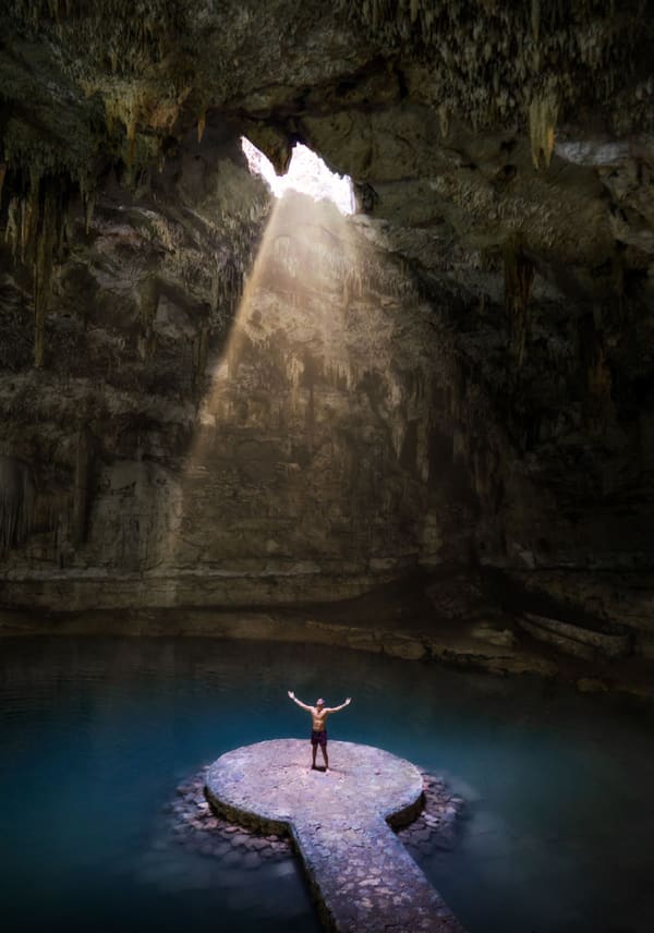 Sunbeam streaming into a blue cenote cavern pool